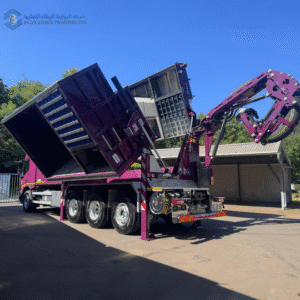 Custom purple MTS suction excavator with dual raised containers and extended suction boom during unloading.