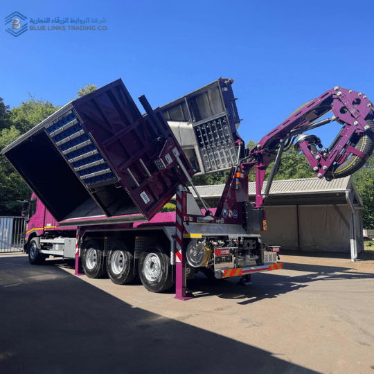 Custom purple MTS suction excavator with dual raised containers and extended suction boom during unloading.
