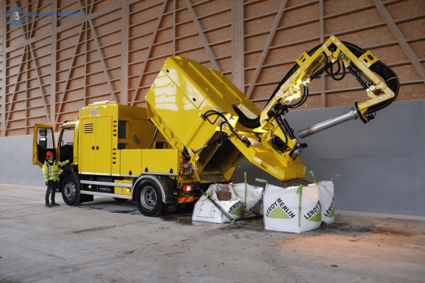 DINOCITY suction excavator performing controlled material discharge in an indoor industrial environment